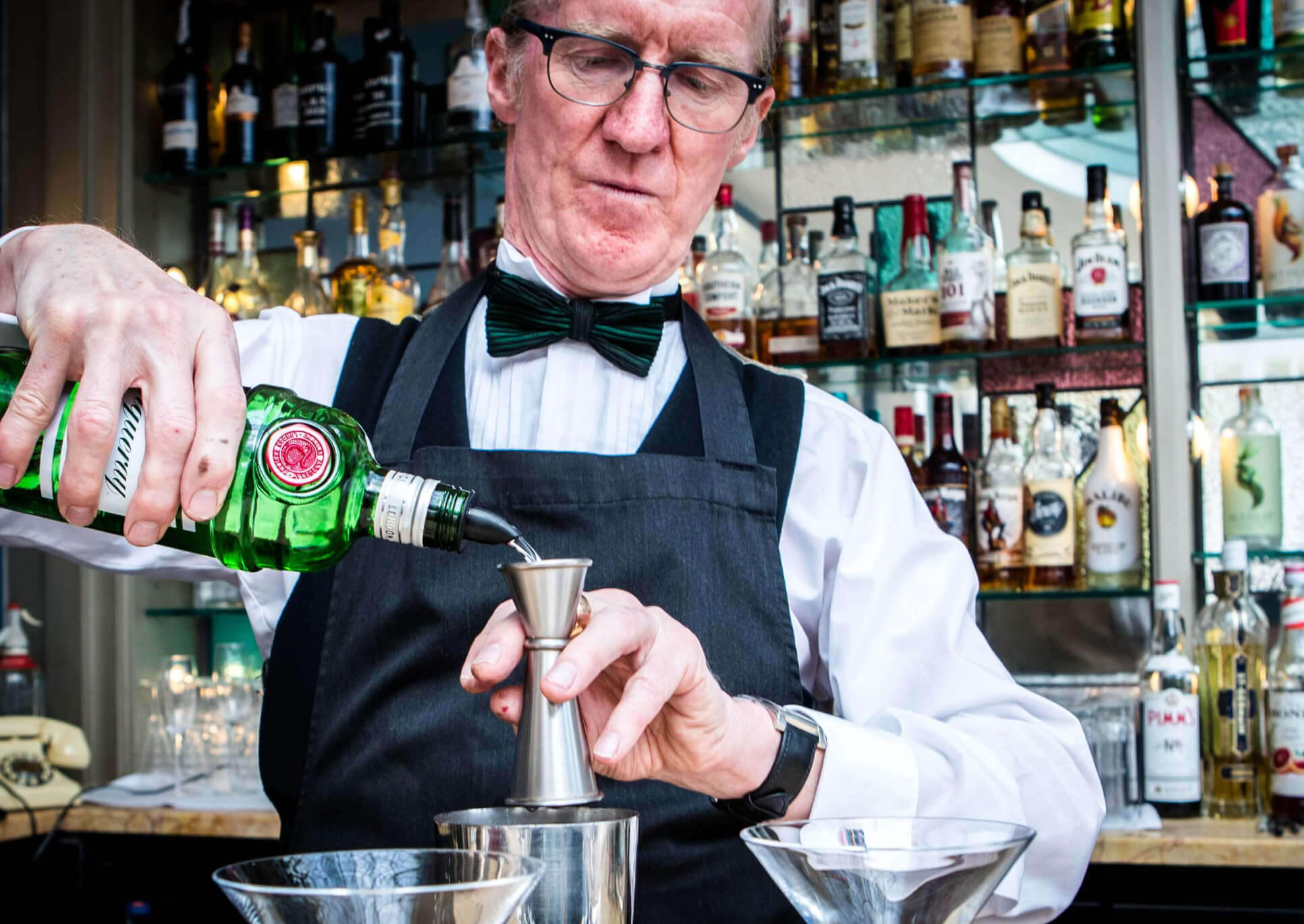 Bar man making a drink in front of a bar