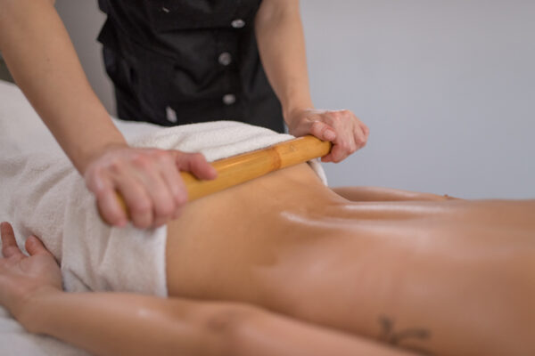 Woman is getting massage with bamboo stick in spa